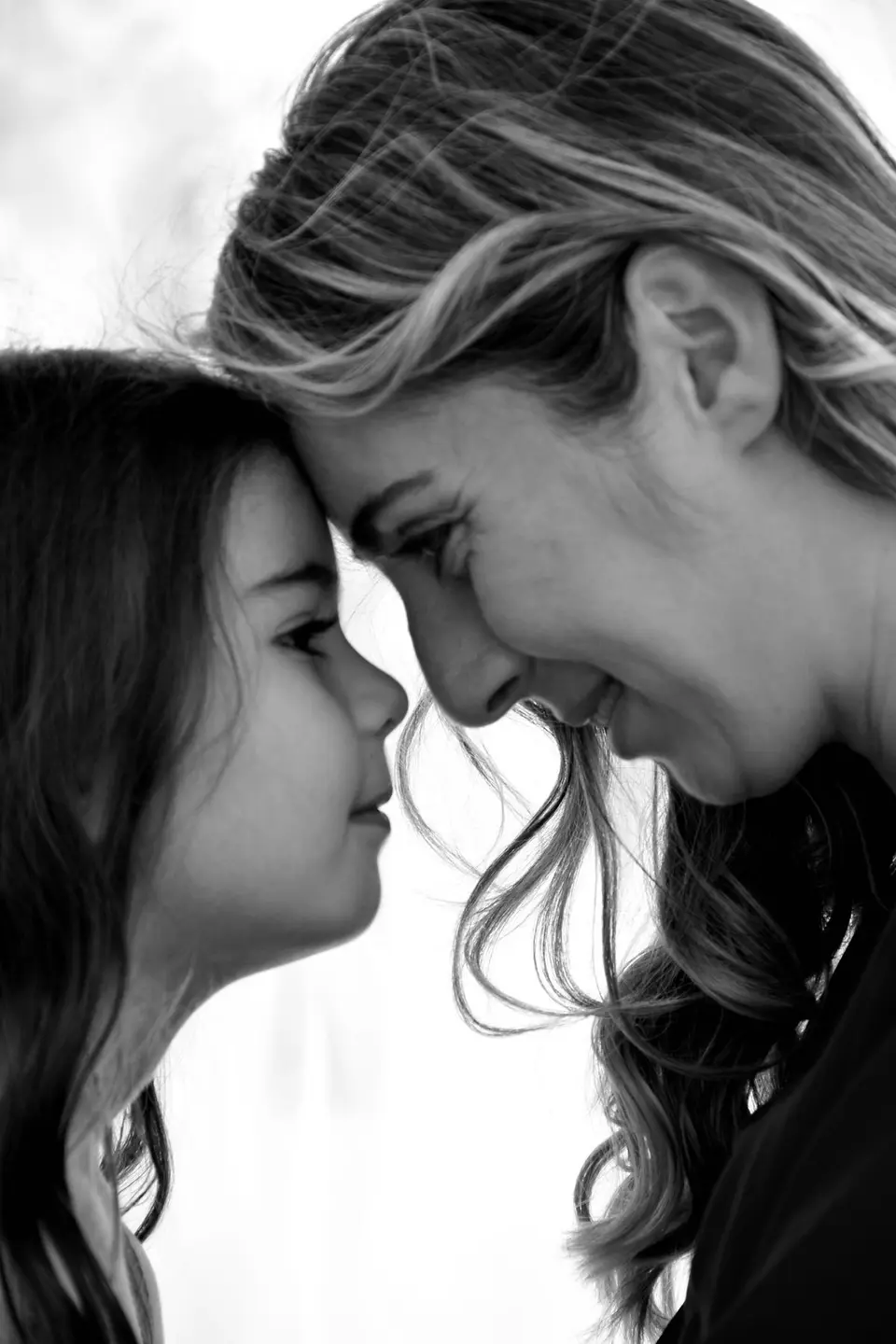Intimate black and white portrait of a mother and daughter sharing a close moment.