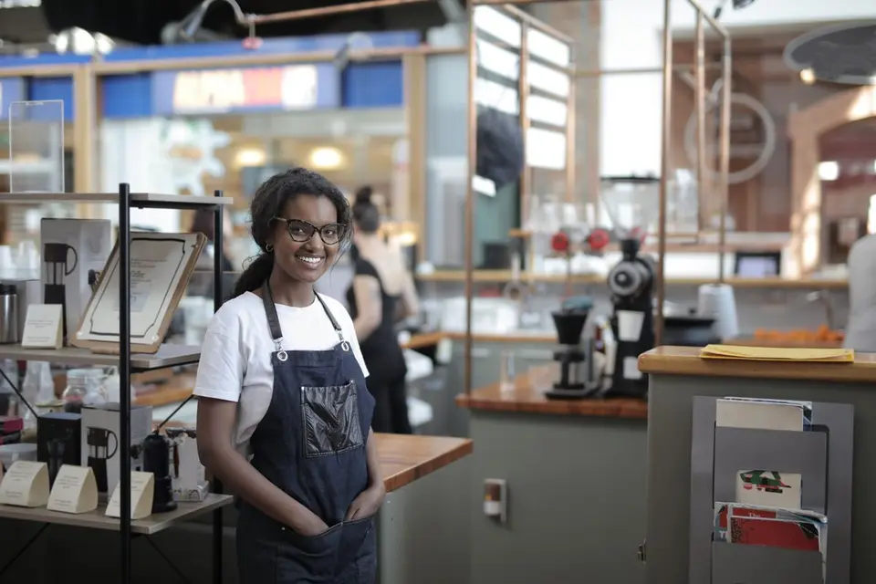 Smiling barista standing in a stylish café, showcasing entrepreneurial spirit.