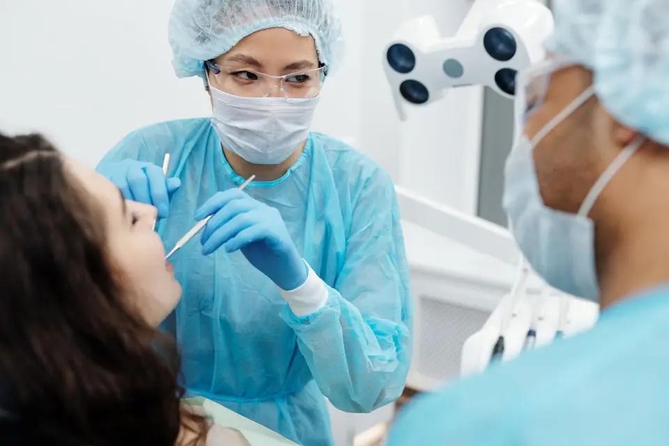 A dentist in protective gear examines a patient in a modern dental clinic.
